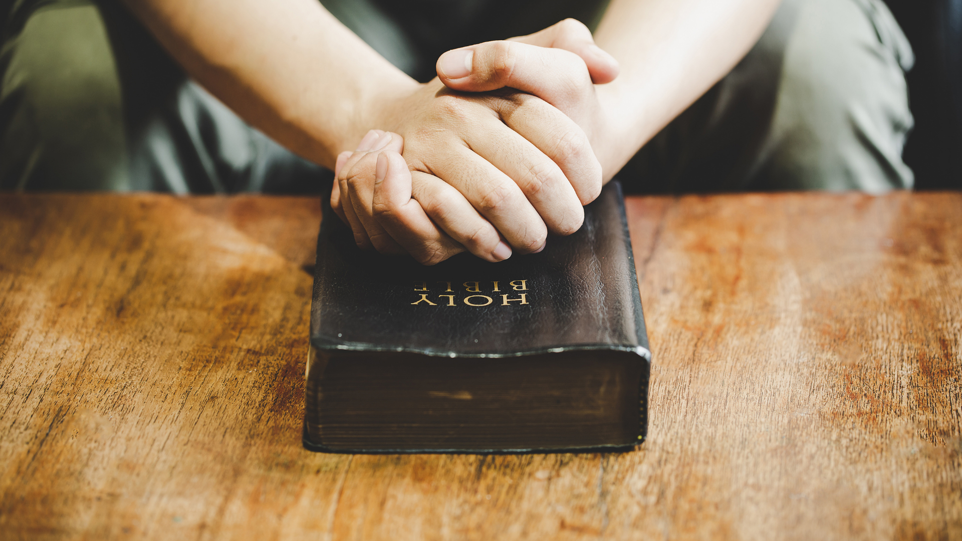 Pessoa com as mãos unidas sobre a bíblia