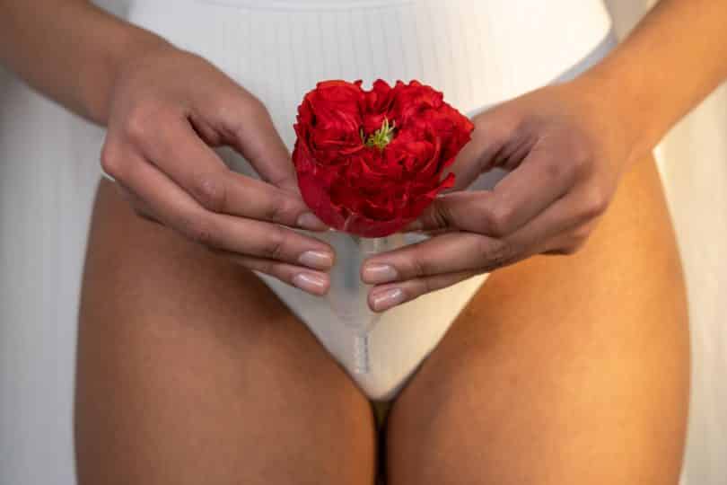 Mulher segurando coletor menstrual junto com uma flor