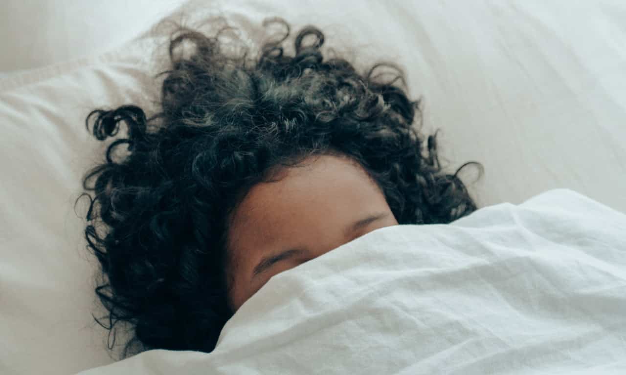 Menina dorme com tecido sobre o rosto.