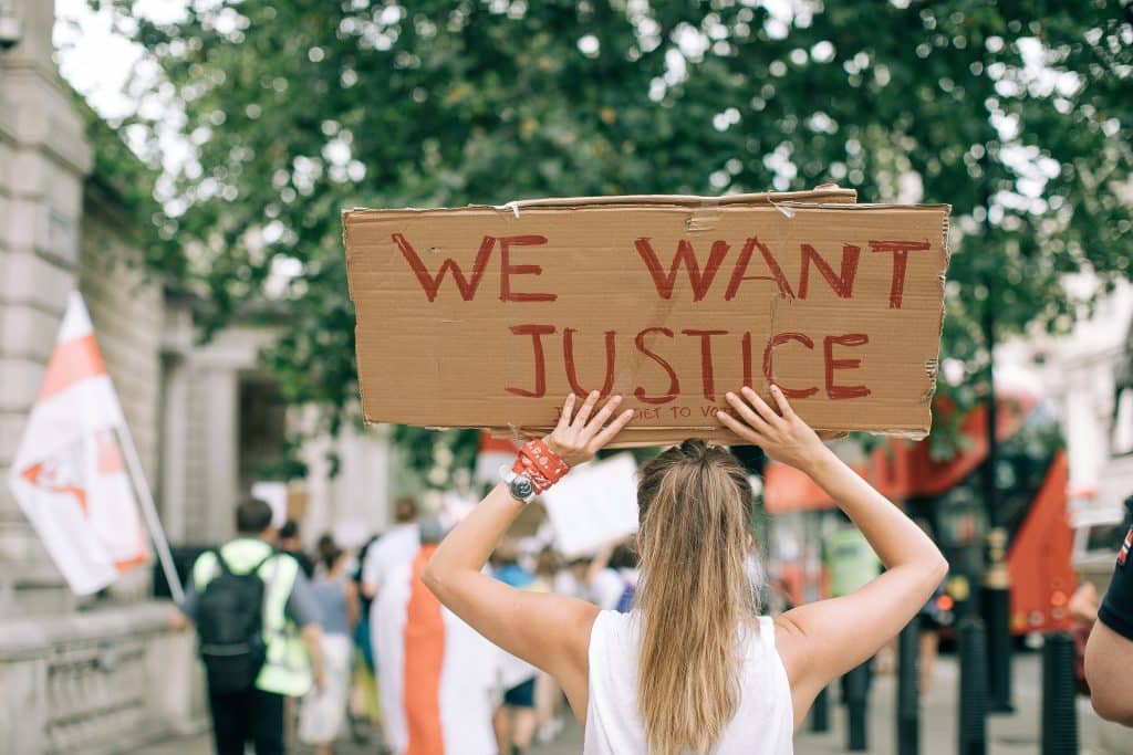 Mulher segurando cartaz escrito "Nós queremos justiça"