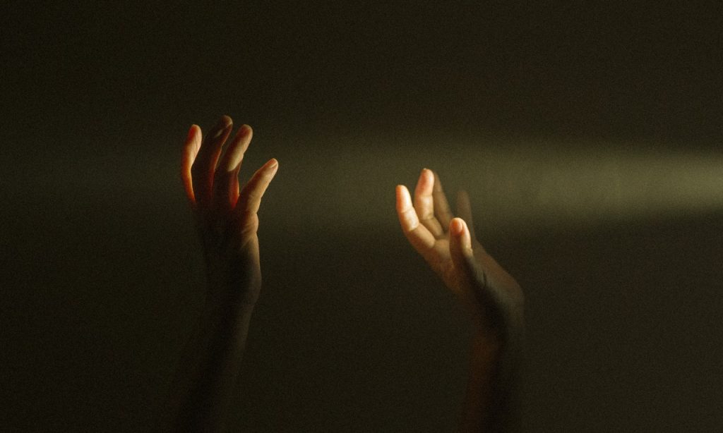 Mãos erguidas em direção à luz. 