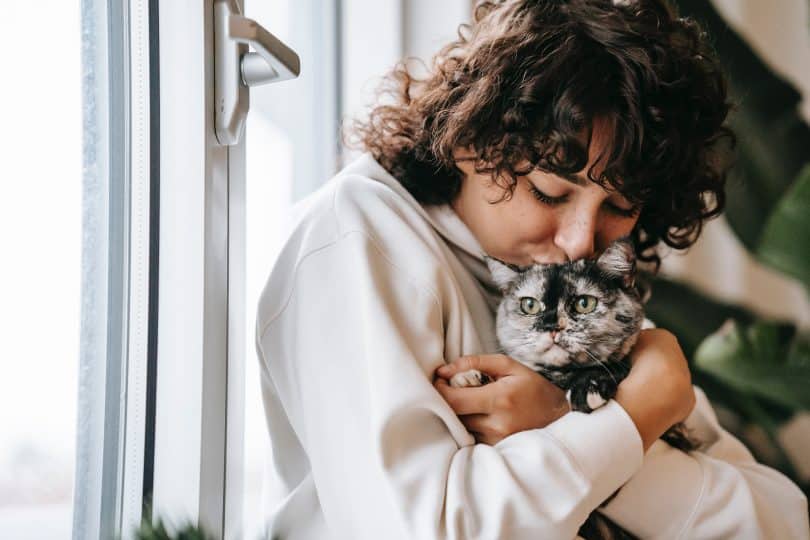 Mulher abraçando e beijando gatinho