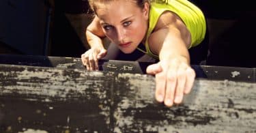 Mulher determinada escalando uma parede de madeira