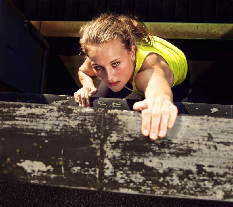 Mulher determinada escalando uma parede de madeira