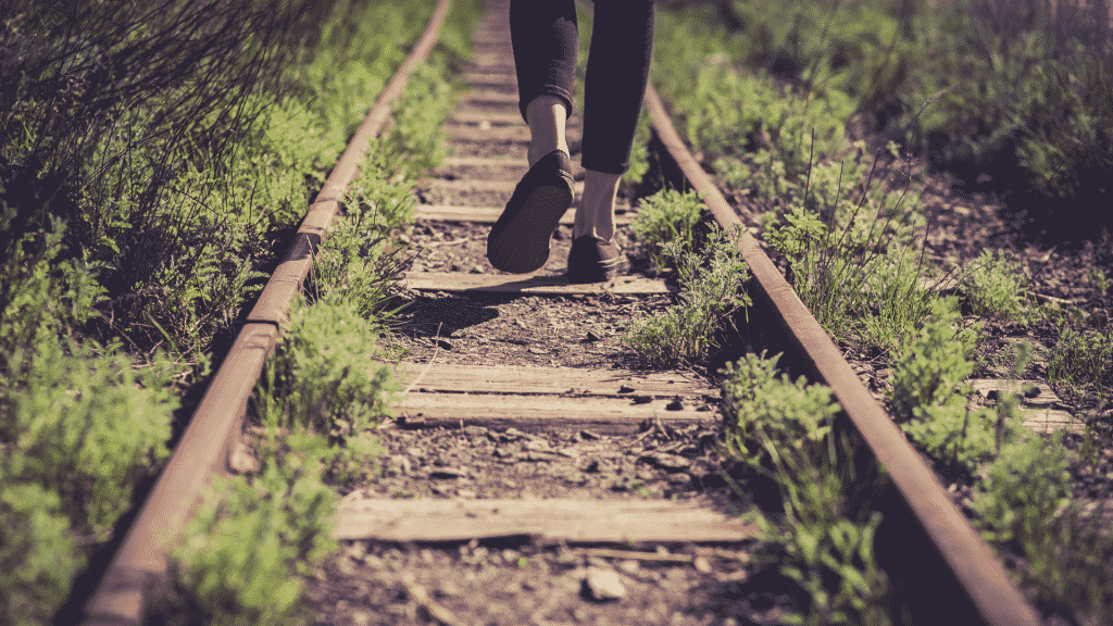 Pessoa caminhando sobre os trilhos do trem desativados