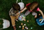 Crianças brancas brincando com ovos coloridos.