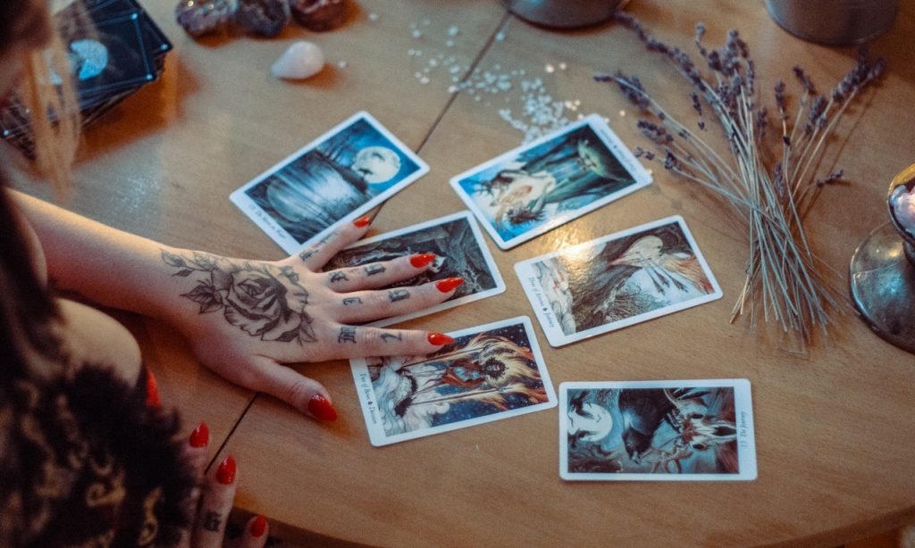 Cartas de tarot postas sobre mesa. Uma mulher as manipula.