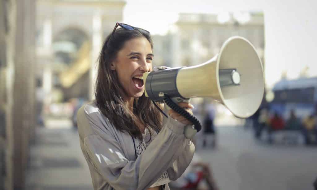 Mulher falando em um megafone.