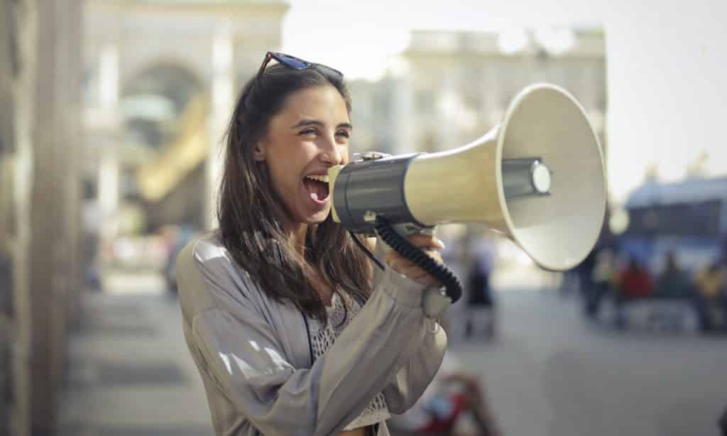 Mulher falando em um megafone. 