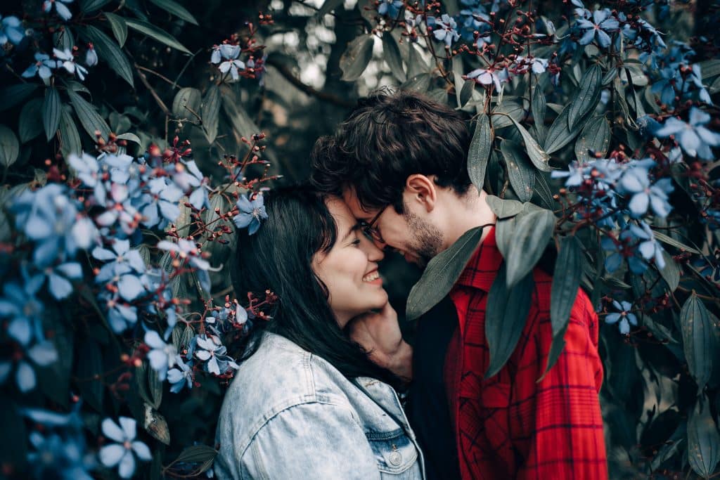 Casal de homem e mulher se olhando ao lado das flores