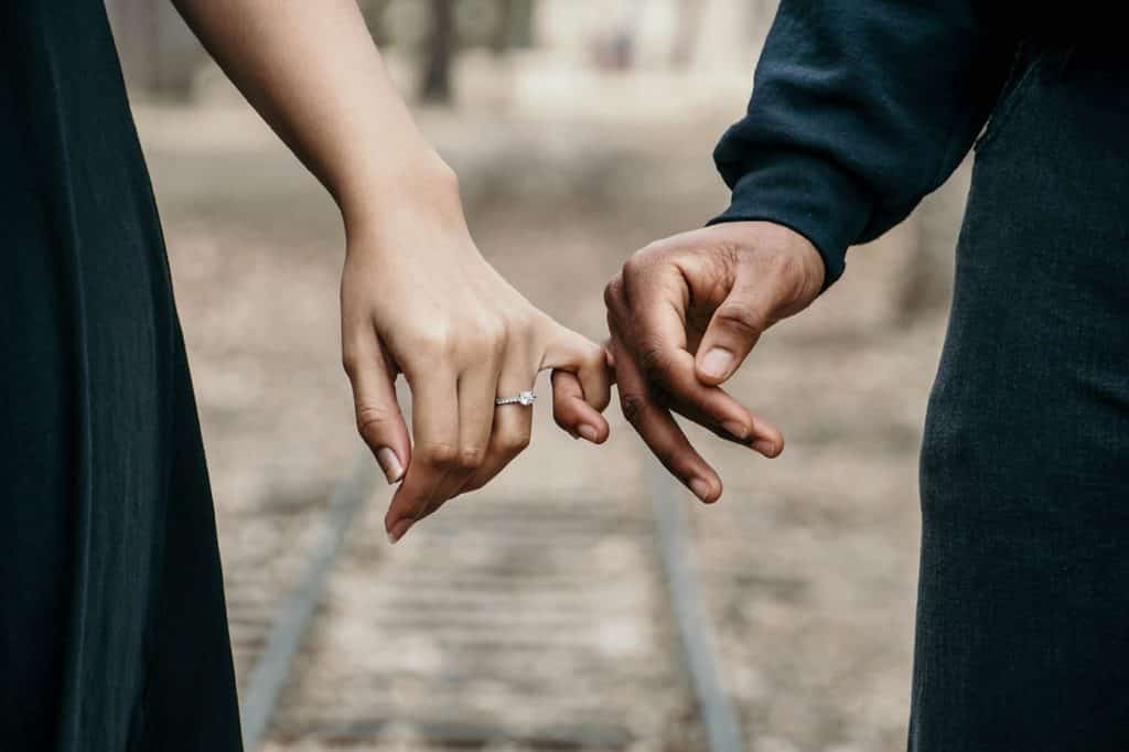 Homem e mulher com seus dedinhos da mão juntos