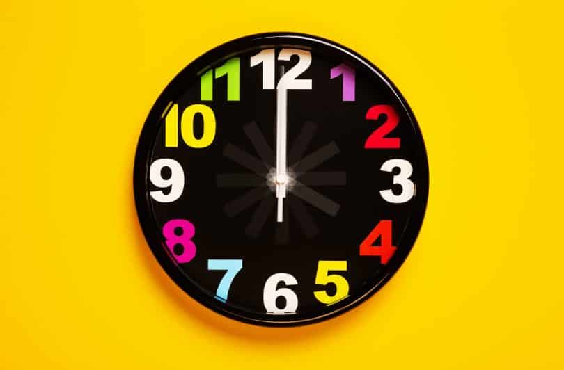 Relógio de parede com números coloridos e plano de fundo amarelo