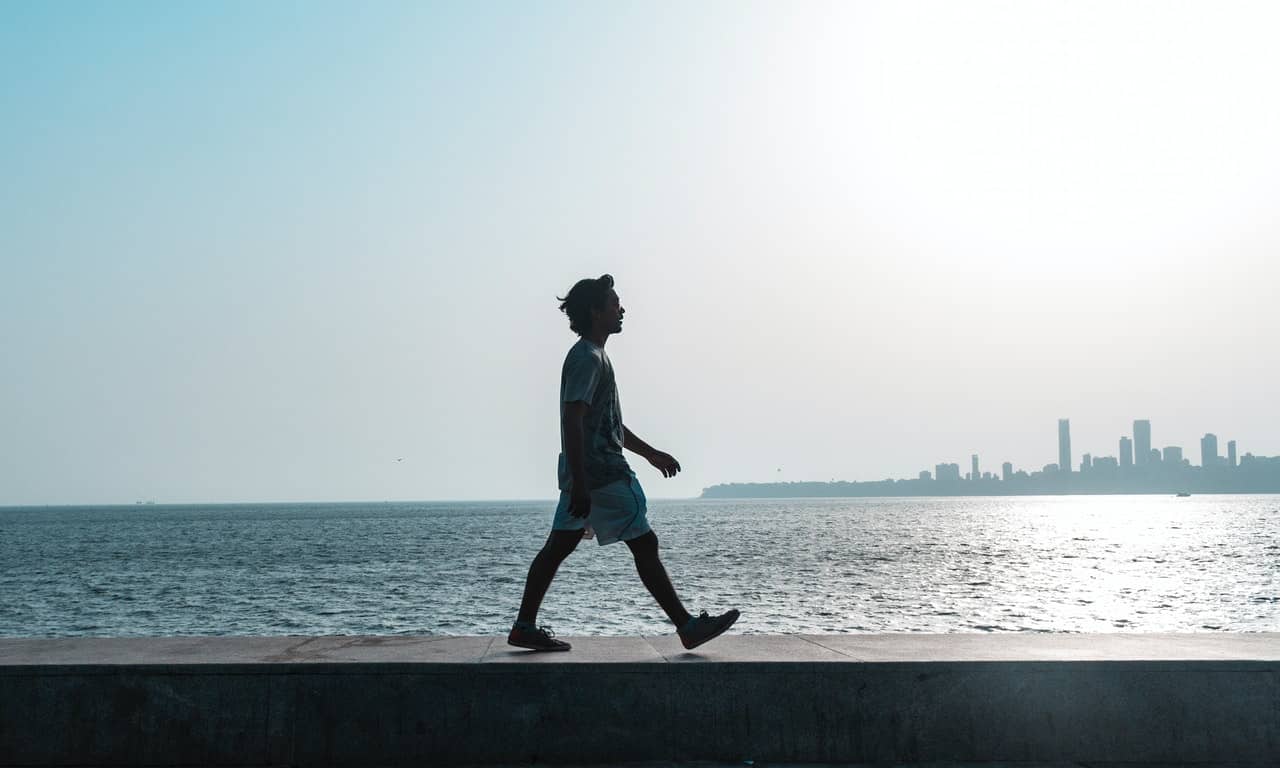 Homem andando à beira de um lago. 