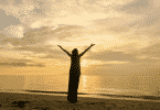 Silhueta de mulher com os braços erguidos na praia