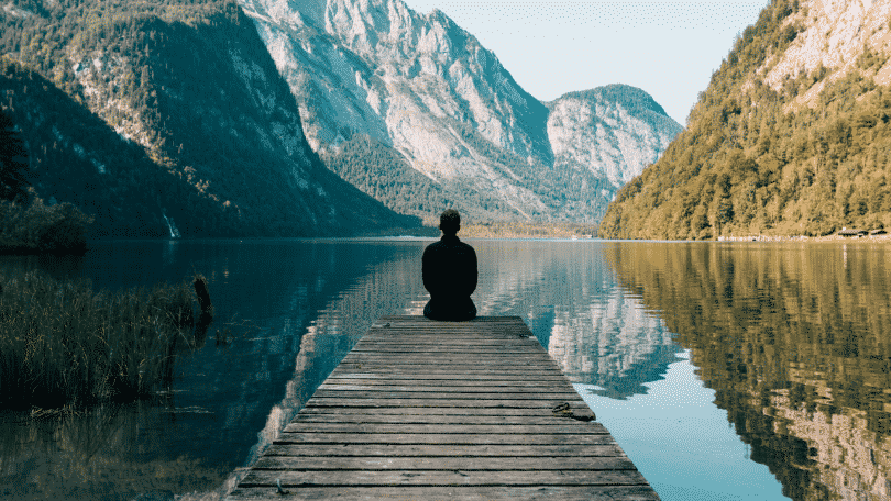 Homem sentado no deck observando o lago