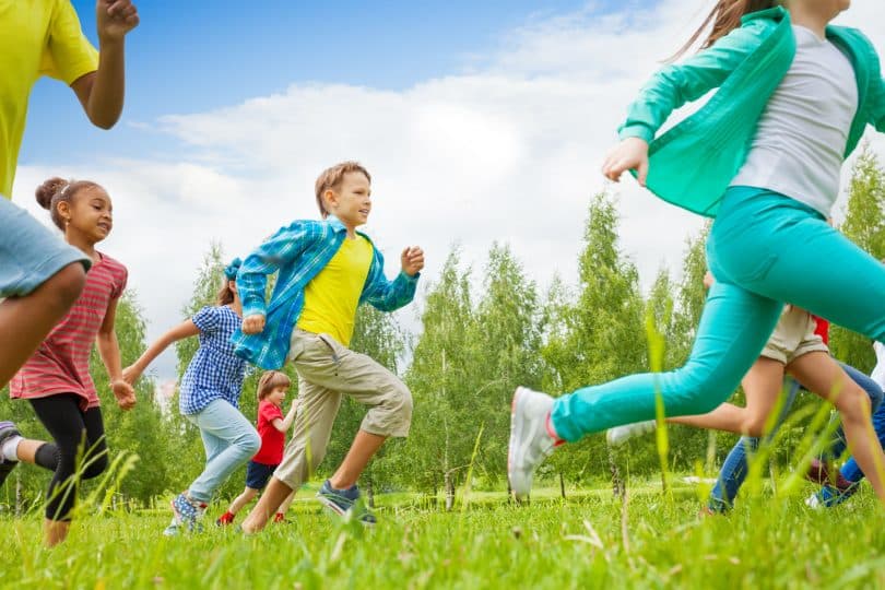 Crianças correm em meio a gramado.