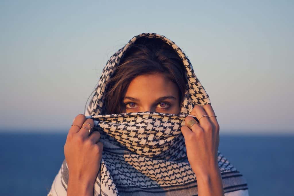 Mulher branca com lenço enrolado na cabeça com os olhos para fora.