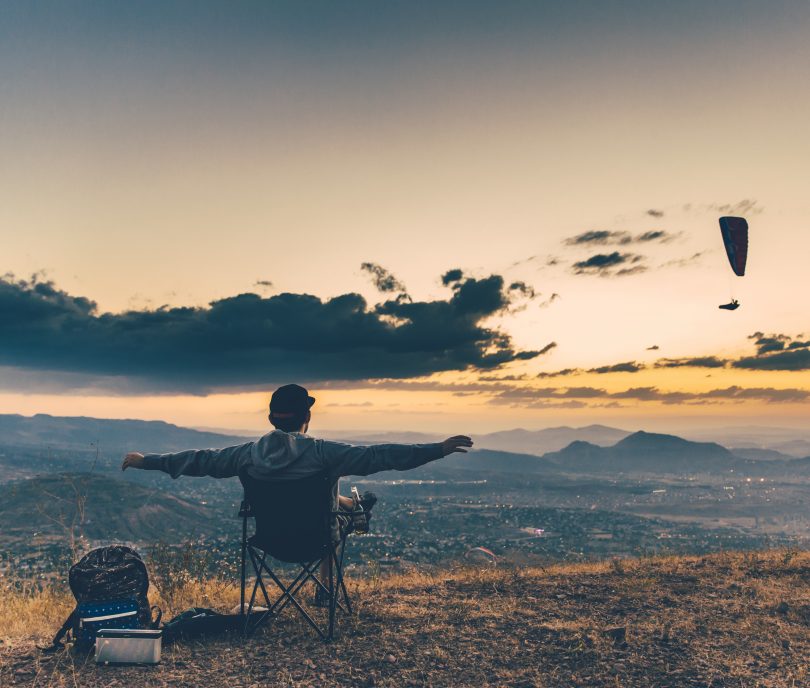 Homem sentado numa cadeira no topo de um morro.