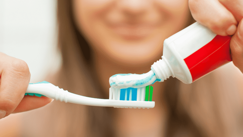 Imagem de uma pessoa colocando pasta de dente em escova