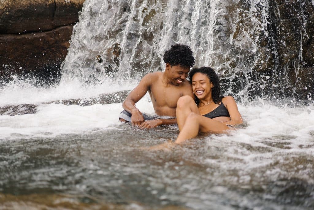 Mulher e homem negros numa cachoeira.