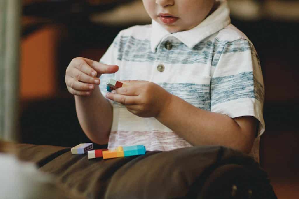 Criança branca brincando com peças coloridas.