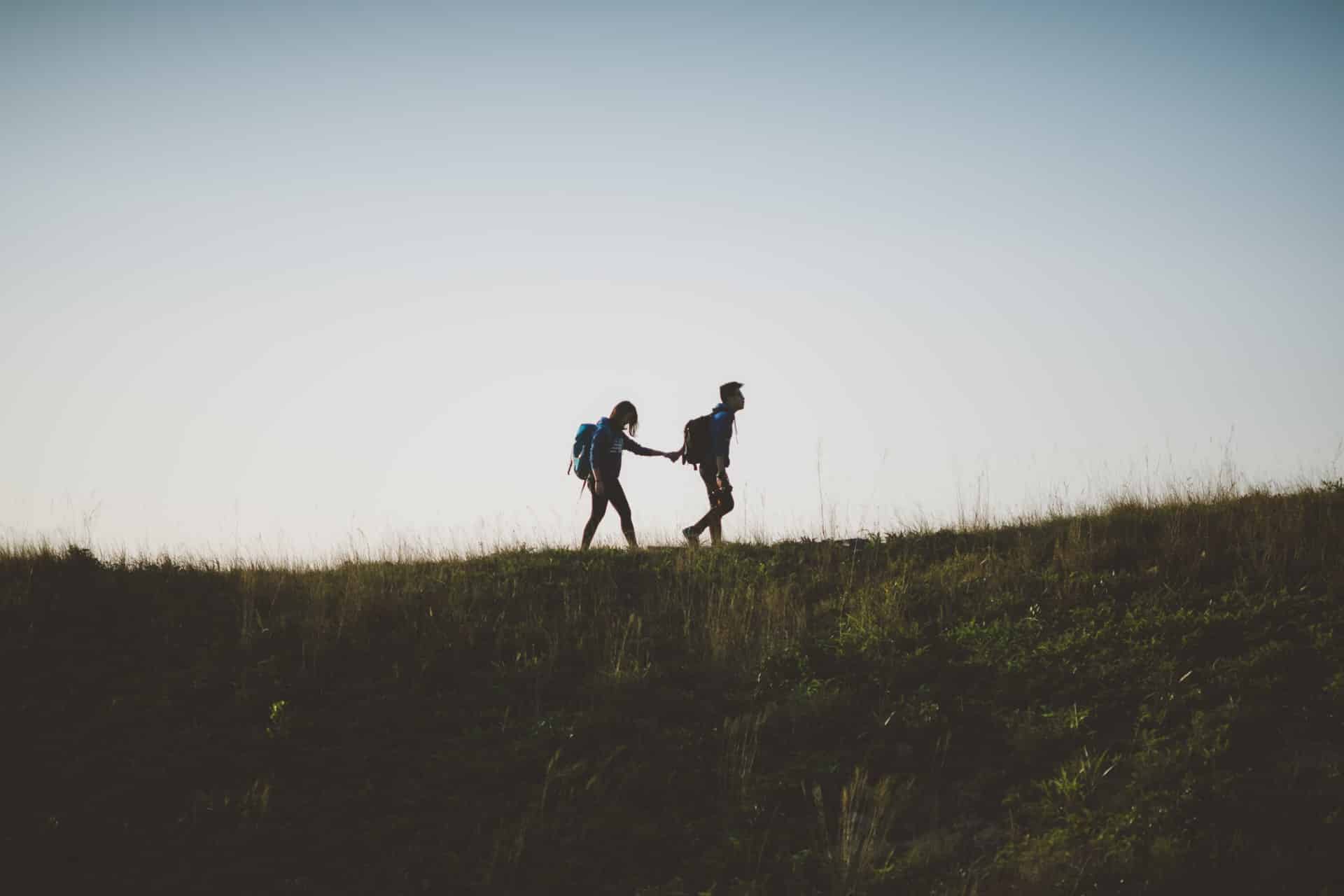Homem e mulher andando de mãos dadas num campo.