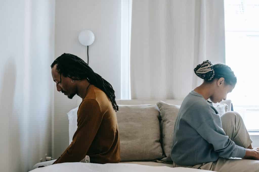 Homem e mulher negros de costas um para o outro.