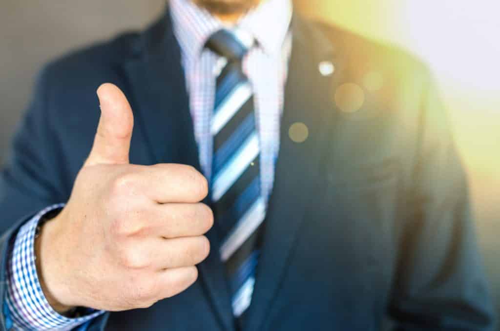 Homem de terno fazendo sinal de positivo com a mão direita