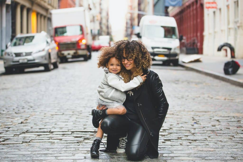 Mulher e menina negras abraçadas.