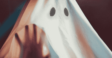 Fantasma de lençol com a mão erguida sobre o pano