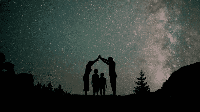 Silhueta de família observando o céu estrelado