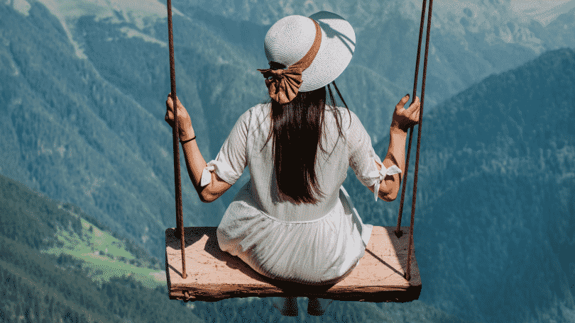 Mulher sentada em balanço no alto de uma montanha