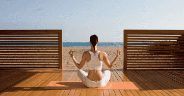 Mulher meditando de frente para a praia