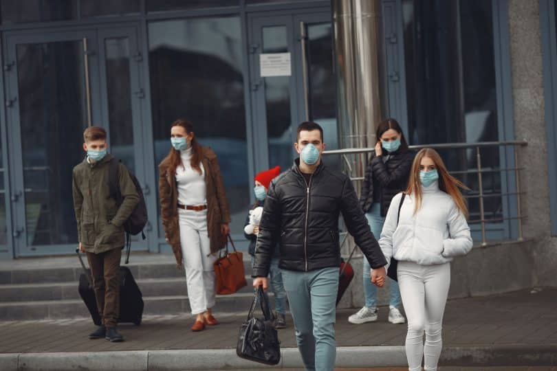 Pessoas de máscara deixam aeroporto.
