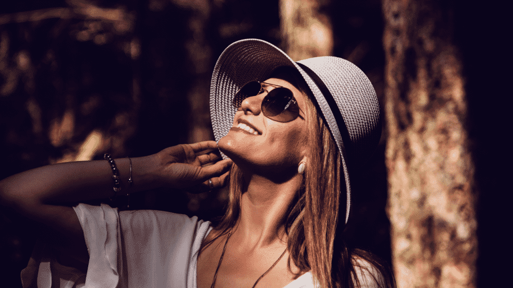 Mulher sorrindo com óculos de sol na floresta
