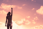 Silhueta de mulher de braço erguido para cima durante por do sol
