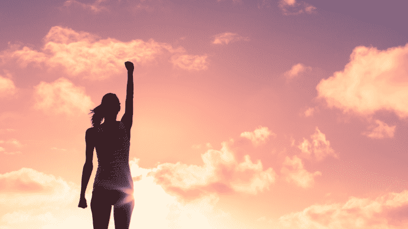 Silhueta de mulher de braço erguido para cima durante por do sol
