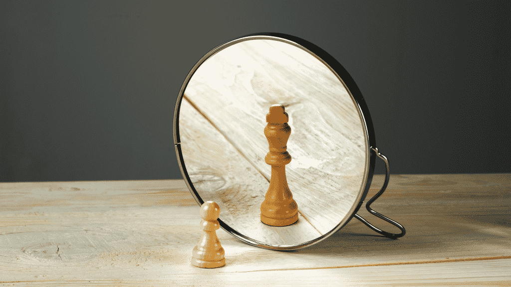 Representação do ego com um peão de xadrez vendo o reflexo como uma rainha