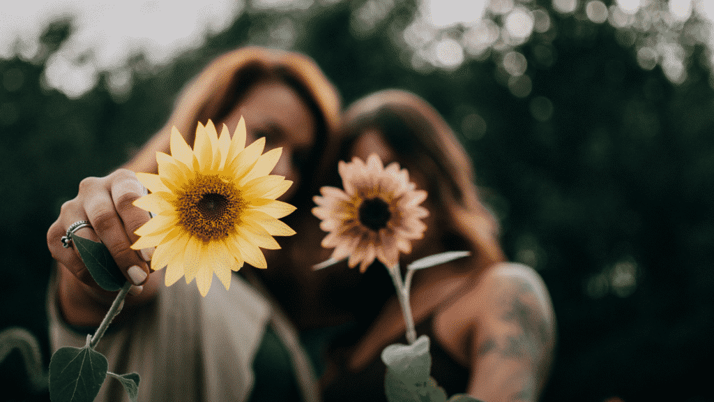 Duas amigas segurando flores em frente à câmera