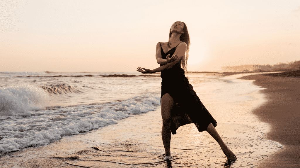 Mulher de vestido dançando descalça na praia