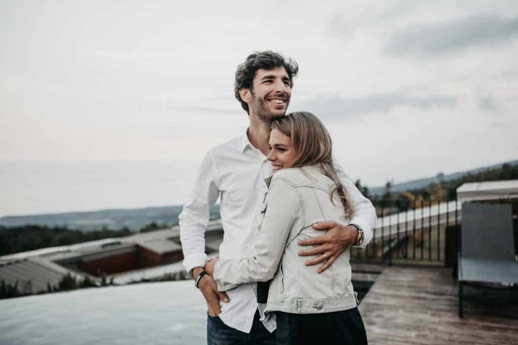 Homem e mulher brancos abraçados sorrindo.