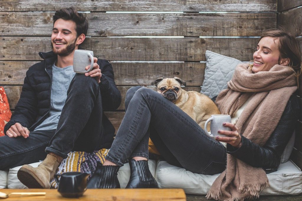 Dois amigos sentados juntos  com um cachorro