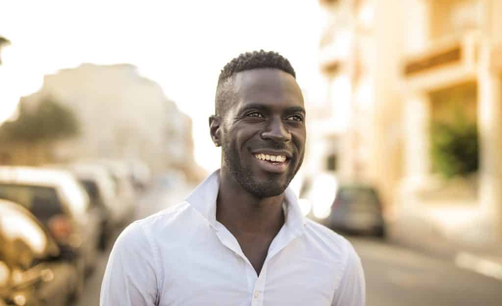 Homem sorrindo em ambiente externo.