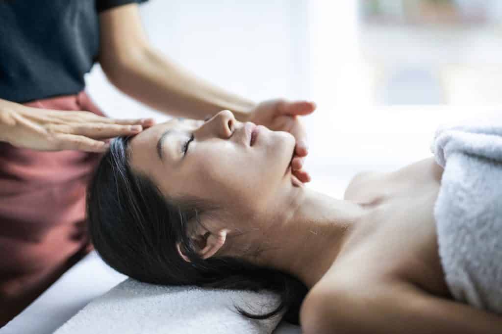 Mulher asiática  recebendo massagem na cabeça.