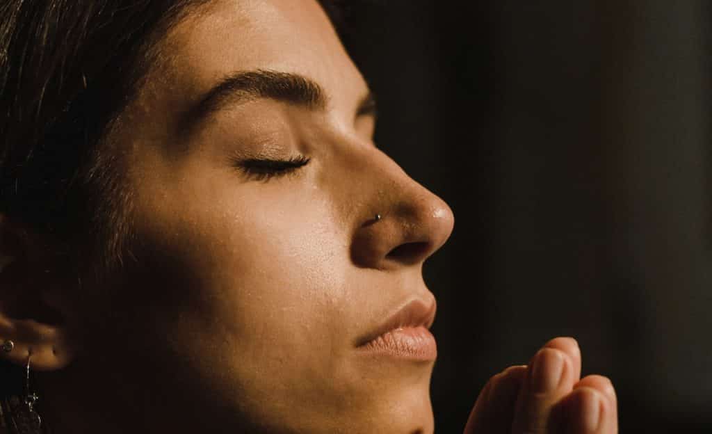 Mulher com olhos fechados ora. 