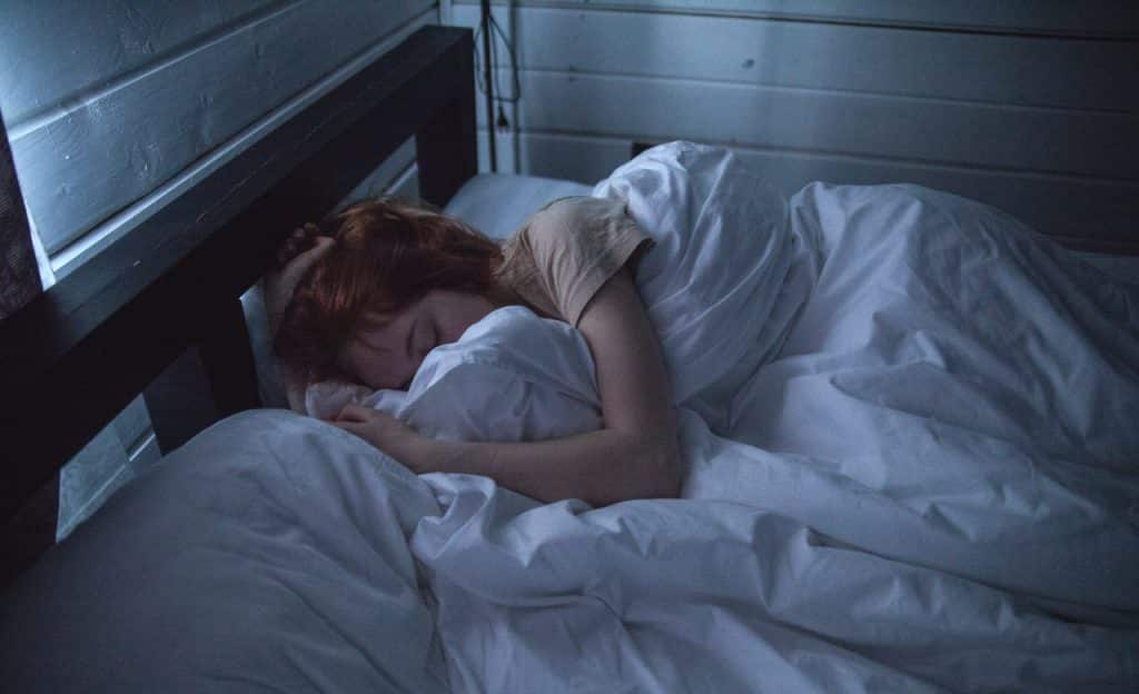 Mulher dorme em cama.