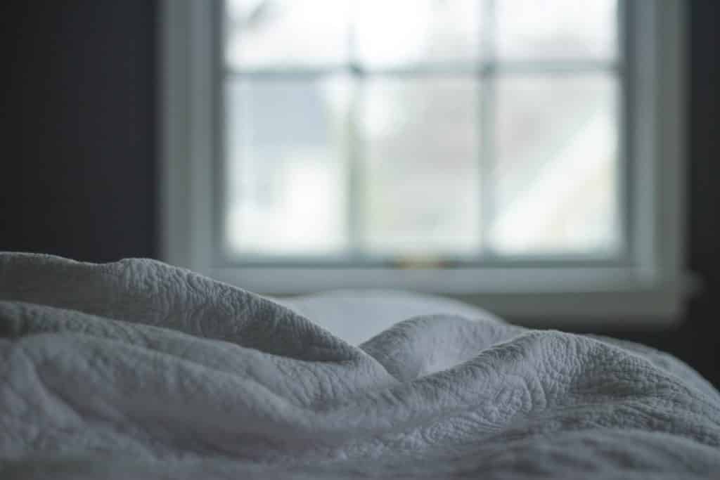 Cobertor branco em cima da cama visto de perto