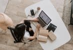 Mulher estudando em frente a um computador com livros ao seu lado