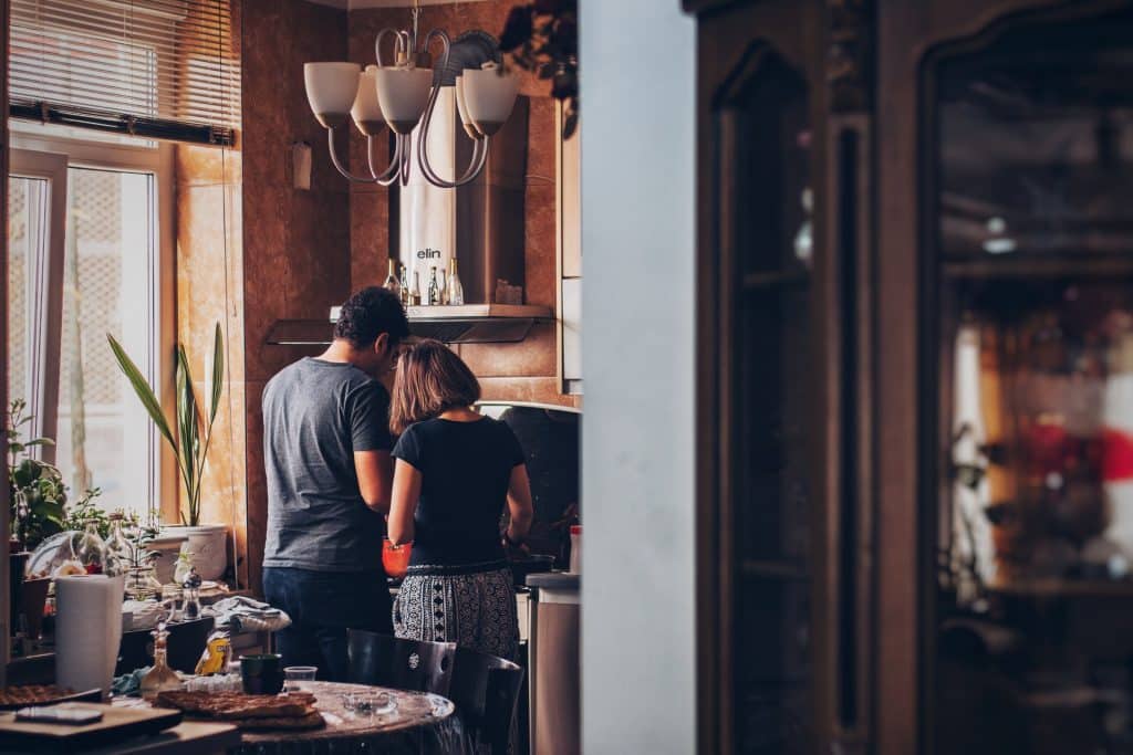 Homem e mulher brancos de costas numa cozinha.