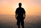 Silhueta de homem na praia observando o por do sol